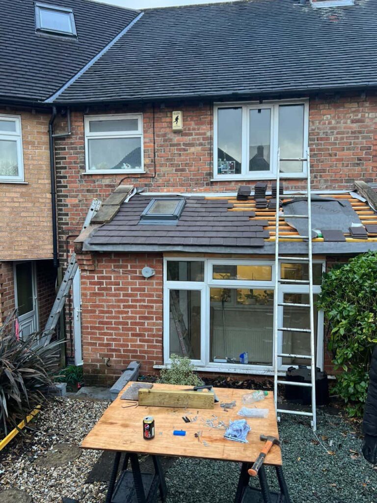 This is a photo of a roof extension that is having new roof tiles installed. This is a photo taken from the roof ridge looking down a tiled pitched roof on to a flat roof. Works carried out by Burgess Hill Roofing Repairs