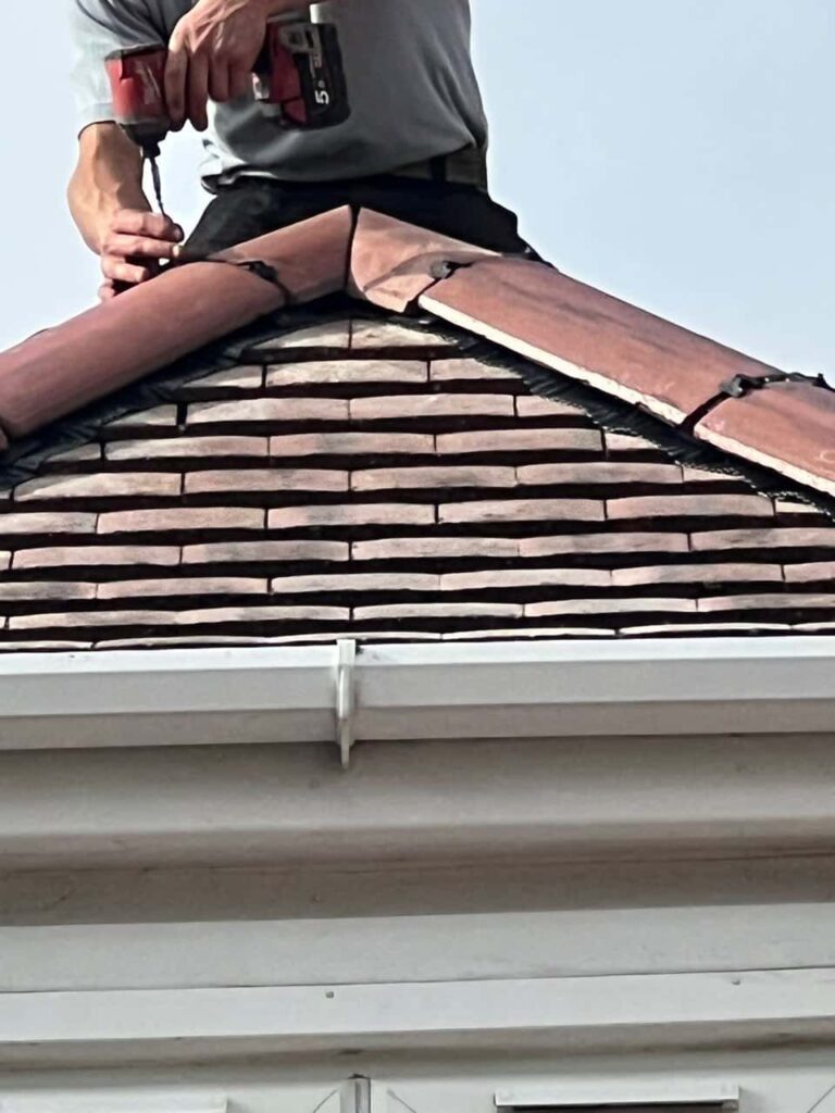 This is a photo of one of the operatives of Burgess Hill Roofing Repairs installing new ridge tiles